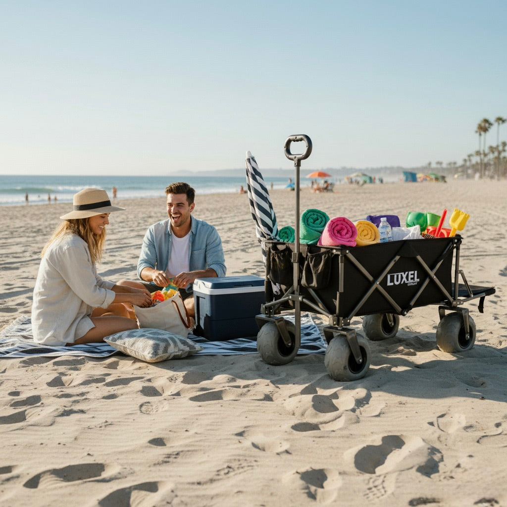 Two people sitting on a beach with a Luxel wagon filled with beach items.