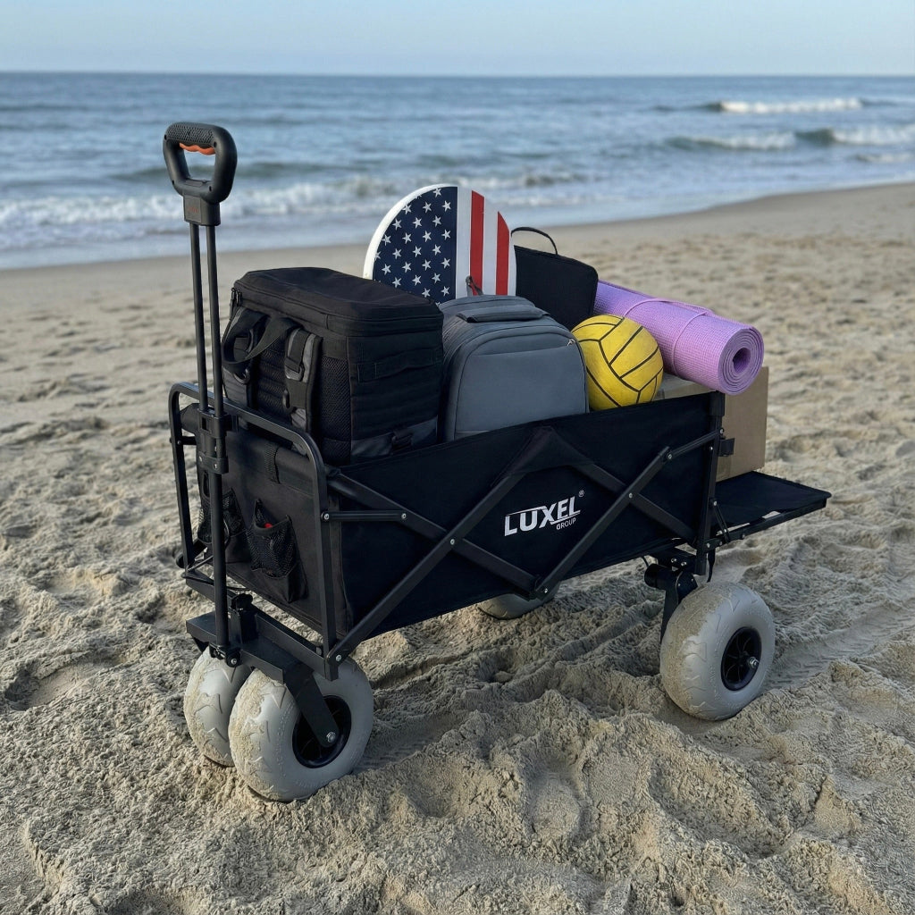 Black Luxel beach cart with beach gear on a sandy beach.
